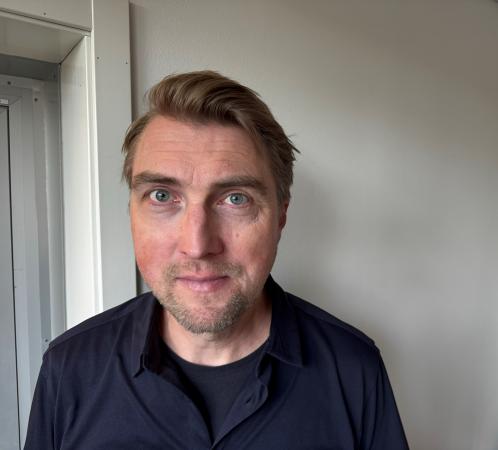 Jonas har mellanblont hår och är klädd i svart.