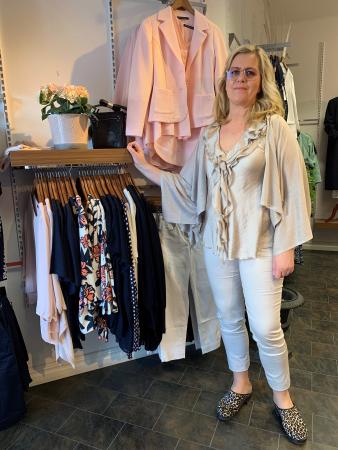 Malin är lång och blond och har glasögon. Hon är klädd i en beige kråsskjorta med matchande jeans och en guldglittrig poncho