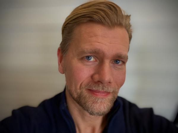 Christoffer är blond och har bakåtkammat hår. Han har skägg och blå ögon. Han ser glad ut.