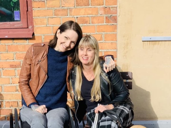 Yasmin har halvlångt, mörkt hår och sitter med huvudet mot Anna som har långt, blont hår.