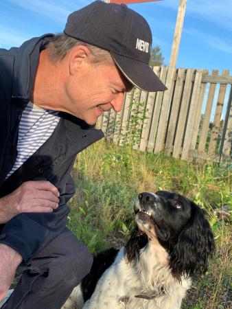 Mikael har blå kepa och tittar på sin hund Zigge som är brun och vit. Zigge tittar troget på husse.