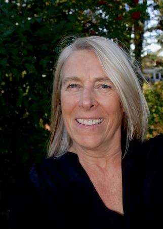 Stina är blond, bär glasögon och ser glad ut. 