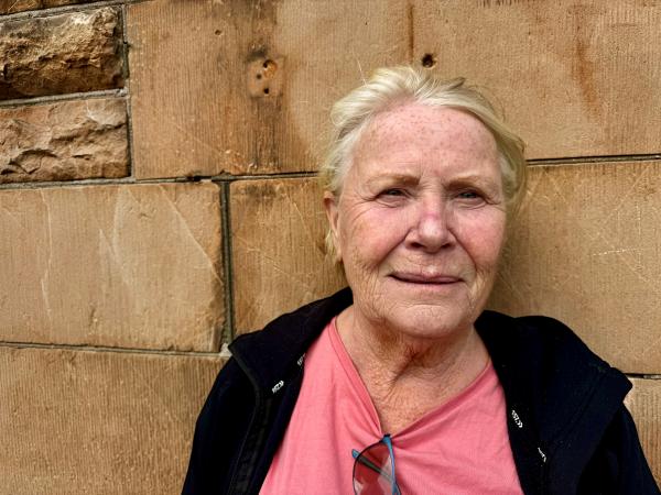 Marianne har ljust hår och många fräknar. Hon har en laxfärgad tröja och svart jacka.