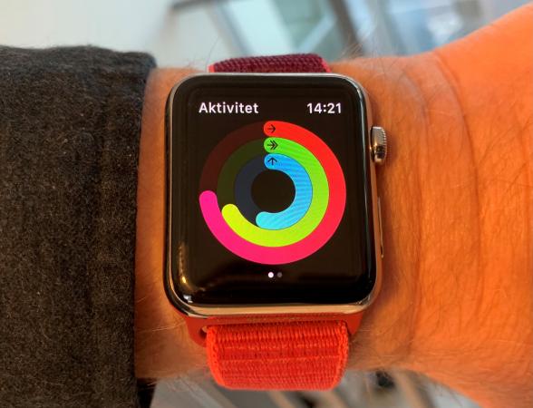 En smart klocka med rött armband och en svart display där man ser färgade cirklar.