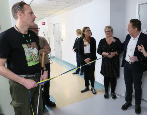 Synskadade Mats Nilsson håller i ena änden av bandet som regionråd Kenneth Backgård är i färd att klippa av.