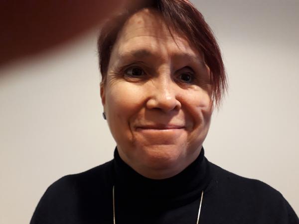 Maria Thorstensson har en kort, brunt hår och har på sig en svart polotröja.Hon tittar rakt in i kameran och ler. 